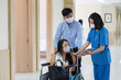 © Thirawatana - The hospital is encouraging the patient in the hospital corridor. Asian patient on hospital wheelchair discussing with female doctor holding tablet.