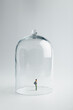Small figurine in quarantine under a glass dome on a bright background with copy space.