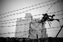 Barbed Wire Stretched Over The Wall With A Multistory Building Seen Far Away In Blur. 