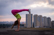 Flexible girl keep balance on hands on the cityscape background . Concept of creativity, balance and individuality