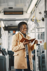 Wall Mural - African American man riding in the city bus. Guy in a brown coat. Man with notebook.