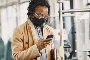 Wall Mural - African American man riding in the city bus. Guy in a brown coat. Corona virus concept.