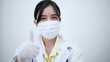 © Pixza - Female doctor wearing protective mask showing thumb up.White background.
