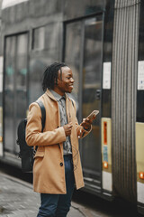 Man by the bus. Guy with mobile phone.