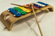 Colorful Xylophone for children with wooden mallets on a white wooden background.