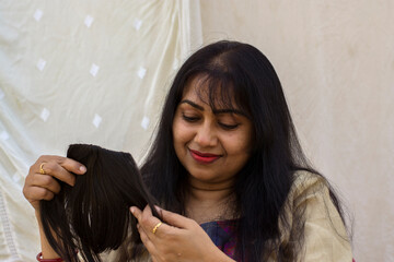 Wall Mural - A beautiful Indian lady getting ready and very happy to see her wig or hair extension