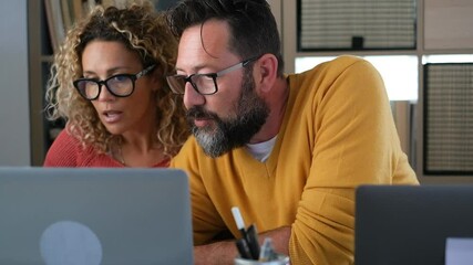 Wall Mural - Young adult man and woman working at home with computer laptop and online internet connection - concept of free office smart working lifestyle and happy people team - couple in video call conference