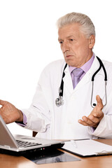 Elderly doctor with a laptop on white background