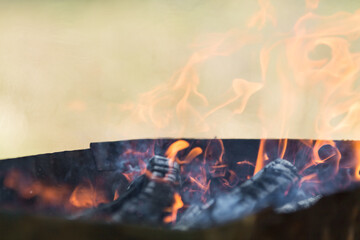 defocused orange flame of a campfire for barbecue in summer on green grass background