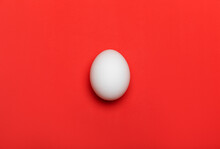 White Egg On Bright Red Background. Close-up Macro Flatlay, With Texture. Food And Easter Concept.