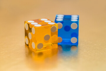 Wall Mural - Two multi-colored glass dice on a gold background. The yellow six and the blue six are behind. Winning concept.