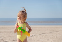 Little Girl With Water Pistol Have Fun At The Beach.