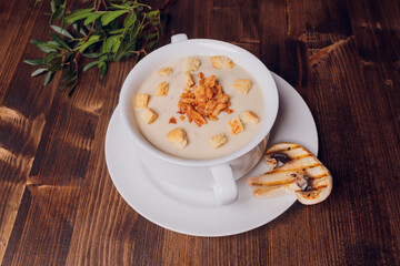 Mushroom soup in white pots, on napkin, on wooden background.