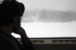 thinking person looking out the train window, young man look at winter landscape from train window, businessman in covid mask travel by train, alone sad men in train