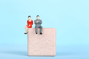 Miniature people with wooden cube on blue background