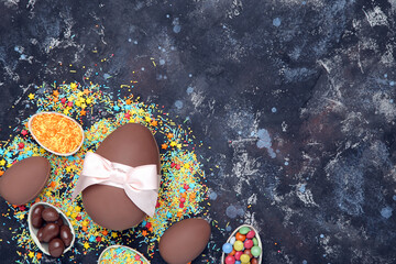 Wall Mural - Easter chocolate eggs with candies and sprinkles on dark background