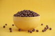 © Andriy - Chocolate cereal corn balls in a yellow bowl scattered on a yellow background. Copy, empty space for text