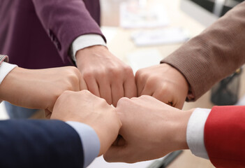 Women holding fists together over table indoors, closeup