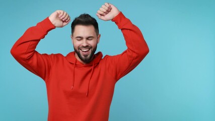 Wall Mural - Cheerful funny young man 20s years old in red streetwear hoodie isolated on blue background studio. People lifestyle concept. Doing dab hip hop dance hands move gesture youth sign hiding covering face