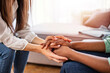 Different ethnicity female friends hold hands during confidential talk close up. Counsellor psychologist provide mental aid to patient at session in clinic, addicted patient professional help concept