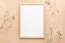 Empty Wooden Frame On Beige Background With Dry Flowers. Mockup Poster Frame Close Up In Neutral Colors. Flat Lay, Top View, Copy Space.