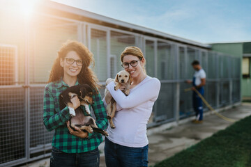 Wall Mural - Two young adult women adopting beautiful dogs at animal shelter.