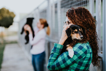 Wall Mural - Two young adult women adopting beautiful dogs at animal shelter.