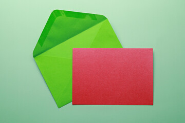 Wall Mural - Green envelope with blank card isolated on green background. Top view