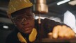 © sorapop - American industrial black young worker man with yellow helmet and ear protection manual rotating on drill machine In order to penetrate workpiece, Engineer at work in industry factory.