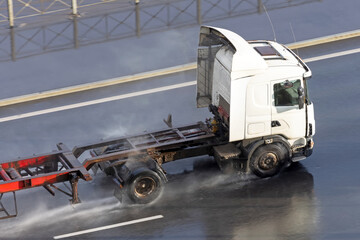 Wall Mural - Truck with trailer and an empty orange long platform driving on wet asphalt after rain.