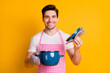 © deagreez - Photo portrait of man in kitchen gloves opening pot holding lid isolated on vivid yellow colored background