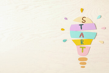 Poster - Lightbulb with word Start made of paper sheets on white wooden background, flat lay. Space for text