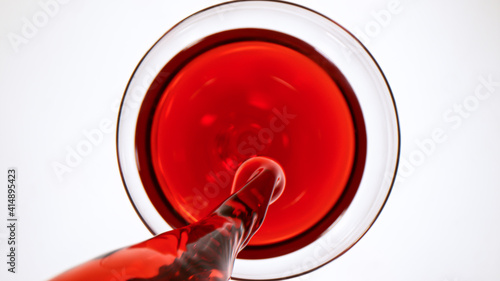 top view of pouring red wine into glass on white background © Lukas Gojda
