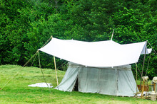 Old White Big Bell Tent Standing On Green Meadow Near Forest. Vintage Medieval Tent