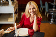 © Svitlana - Lively blonde woman posing for the camera at restaurant table