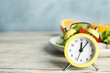 © New Africa - Alarm clock and healthy food on white wooden table, space for text. Meal timing concept