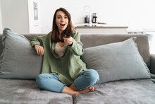 Happy Young Woman Watching Tv On Sofa
