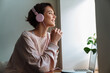 © Drobot Dean - Happy beautiful girl in headphones working with laptop at window