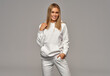 © kiuikson - Beautiful happy blonde woman wear of white set of track suit over gray background