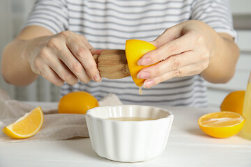 Woman squeezing lemon juice with wooden reamer at table, closeup