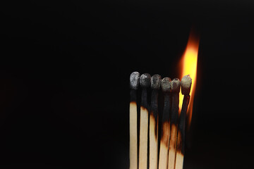 Burning matches on black background. matchsticks on fire in row of burning is sequence while one match stay down from burning to avoid fire connecting against black background