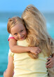 Cute girl hugging her mom on the beach