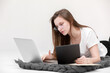 © Andriy Medvediuk - A seriously young girl in glasses sits with a laptop. Education, remote work and blogging. Isolated on a white background.