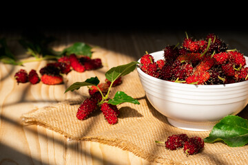 Wall Mural - Fresh organic Mulberrys healthy fruit source of vitamin. Red mulberry in white bowl on the wooden table with sunlight. ingredient for cook dessert and jam.