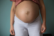 Pregnant Woman In Room Standing And Showing Her Belly.