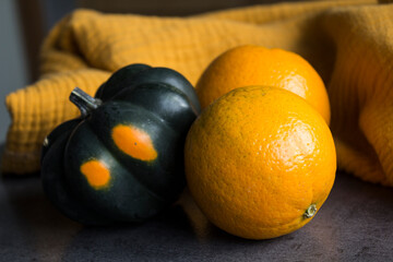 Acorn squash and two oranges on a table. Yellow textured background. Simple composition still life. Healthy eating concept. 