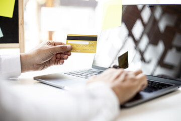 Men hold credit cards and fill in their card information to pay for purchases on the website, credit cards can be used to pay for goods and services with general merchants or online shopping.