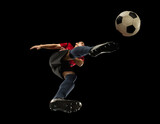 Fototapeta Sport - Young caucasian football, soccer player in action, motion isolated on black background, look from the bottom. Concept of sport, movement, energy and dynamic, healthy lifestyle. Training, practicing.