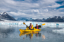 Happy Couple Enjoy Kayaking Near The Glacier  And Iceberg In Alaska