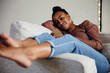© Gerald R Carter Jr/Creative Flame - Black woman relaxing and comfortable on couch looking at cellphone